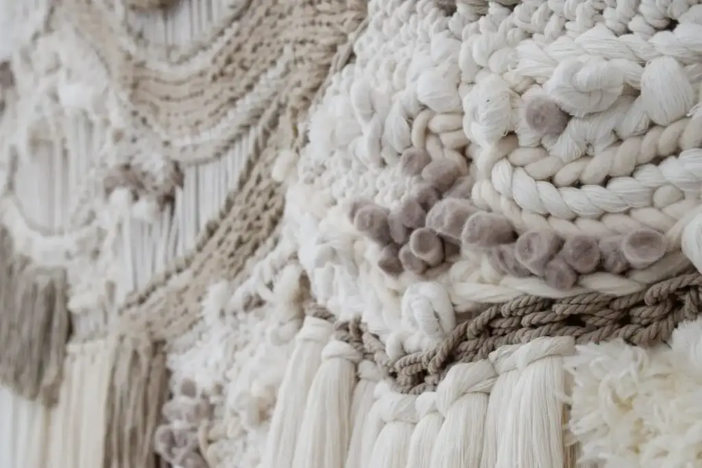 Detalle en primer plano de tapiz artesanal de macramé en tonos crudos y grises, con textura volumétrica · Samore Studio