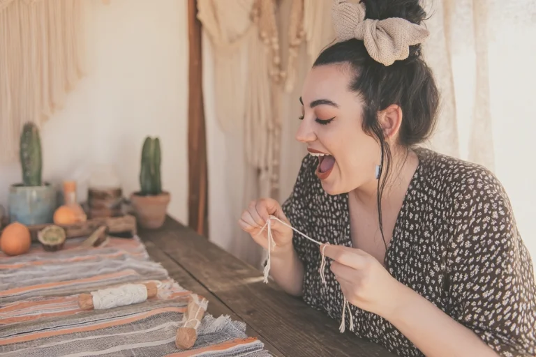 Mujer sonriente mostrando el comienzo de su primer proyecto de macramé en su salón
